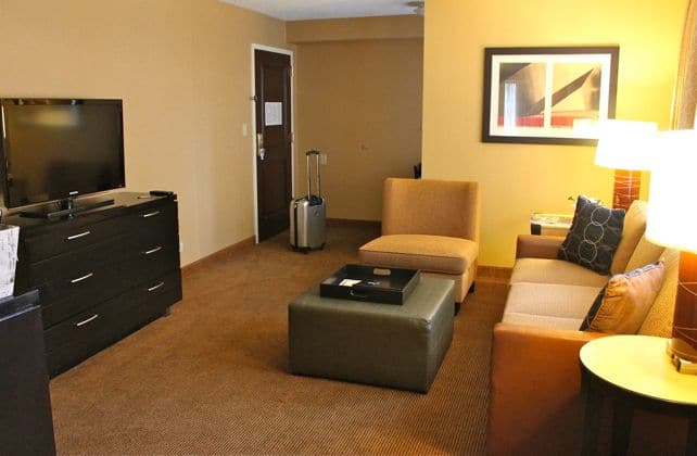 The living room area of the Embassy Suites Chicago Downtown has a pull-out couch, chair and a TV.