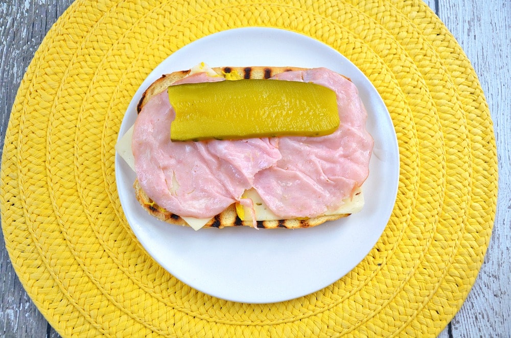 hot dog bun with mustard, ham, Swiss cheese and a sliced pickle