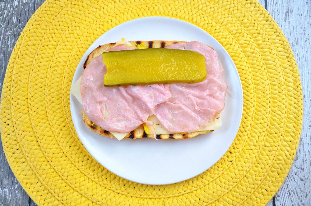 hot dog bun with mustard, ham, Swiss cheese and a sliced pickle