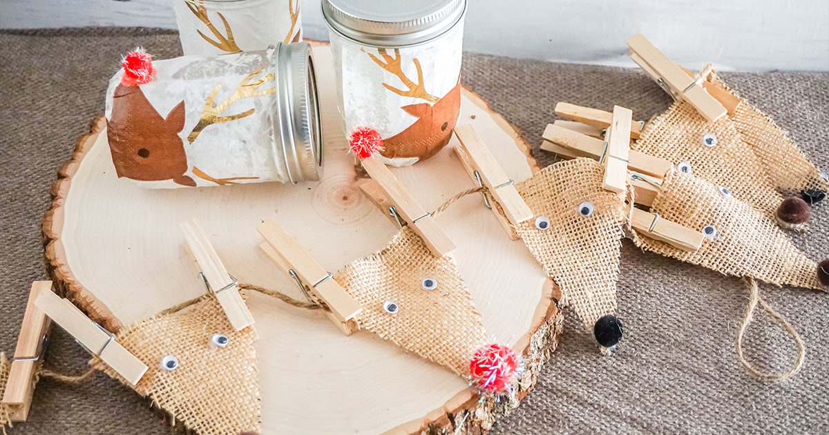 Burlap reindeer banner and jars on a log cutting.