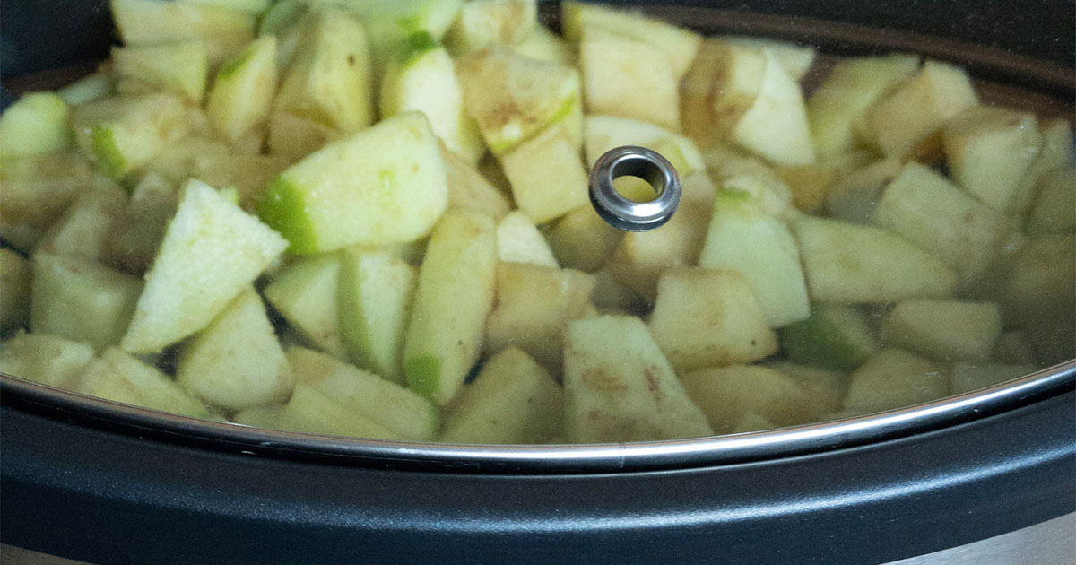 in-process step of apples being cooked in a slow cooker to make apple butter