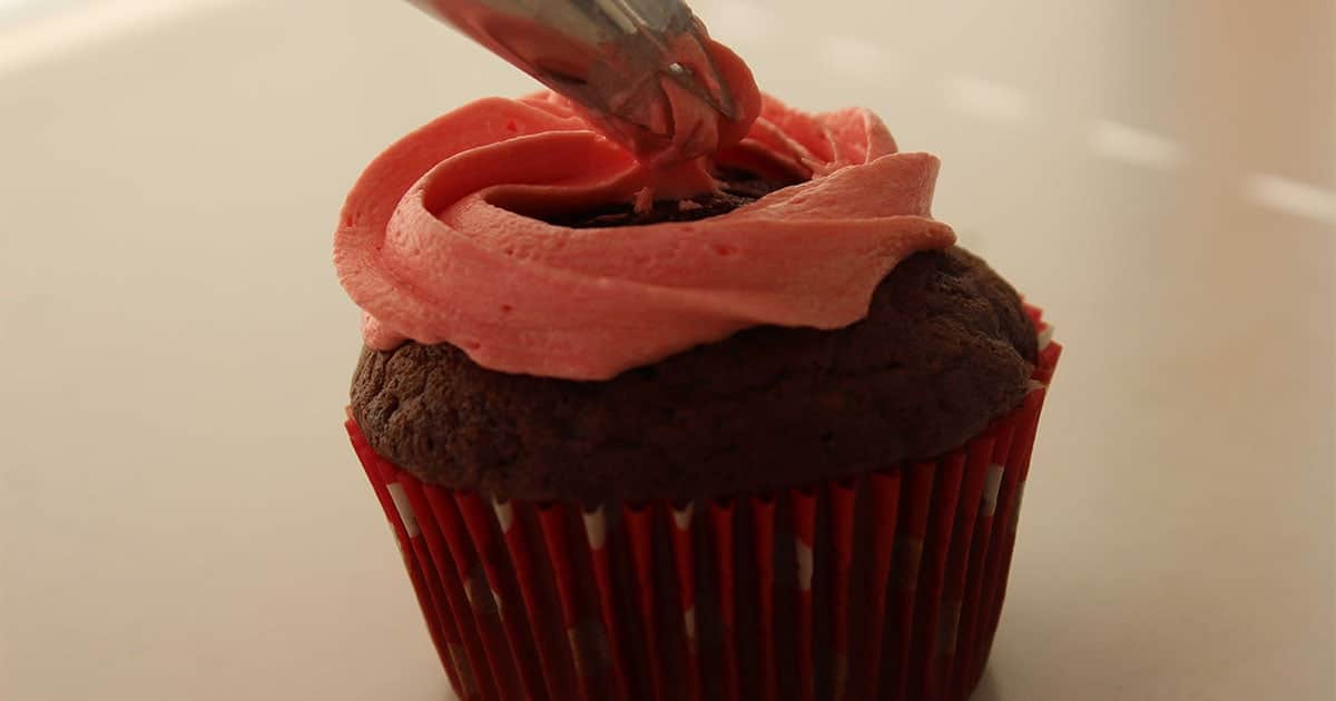 in-process step of icing cherry coke cupcakes