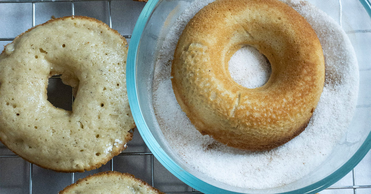 dipping an apple donut into sugar coating