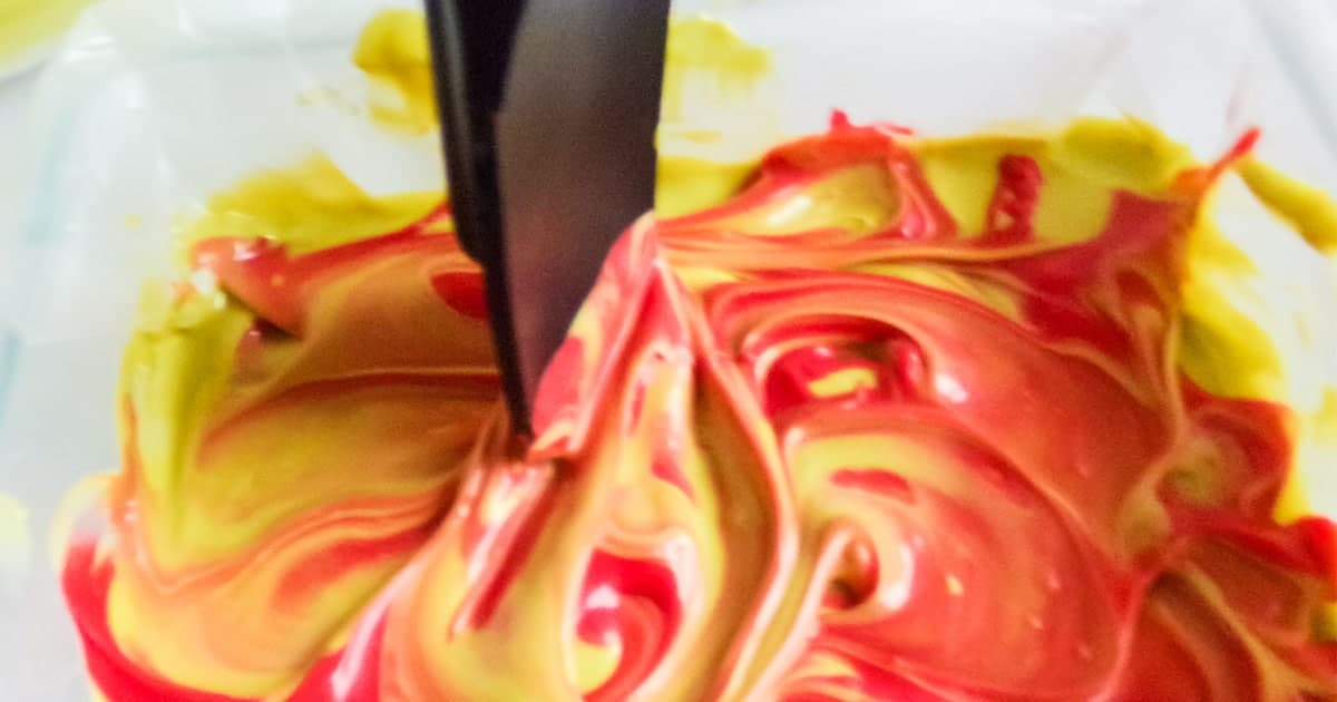 in-process step of swirling red chocolate with green chocolate to make grinch bark for christmas