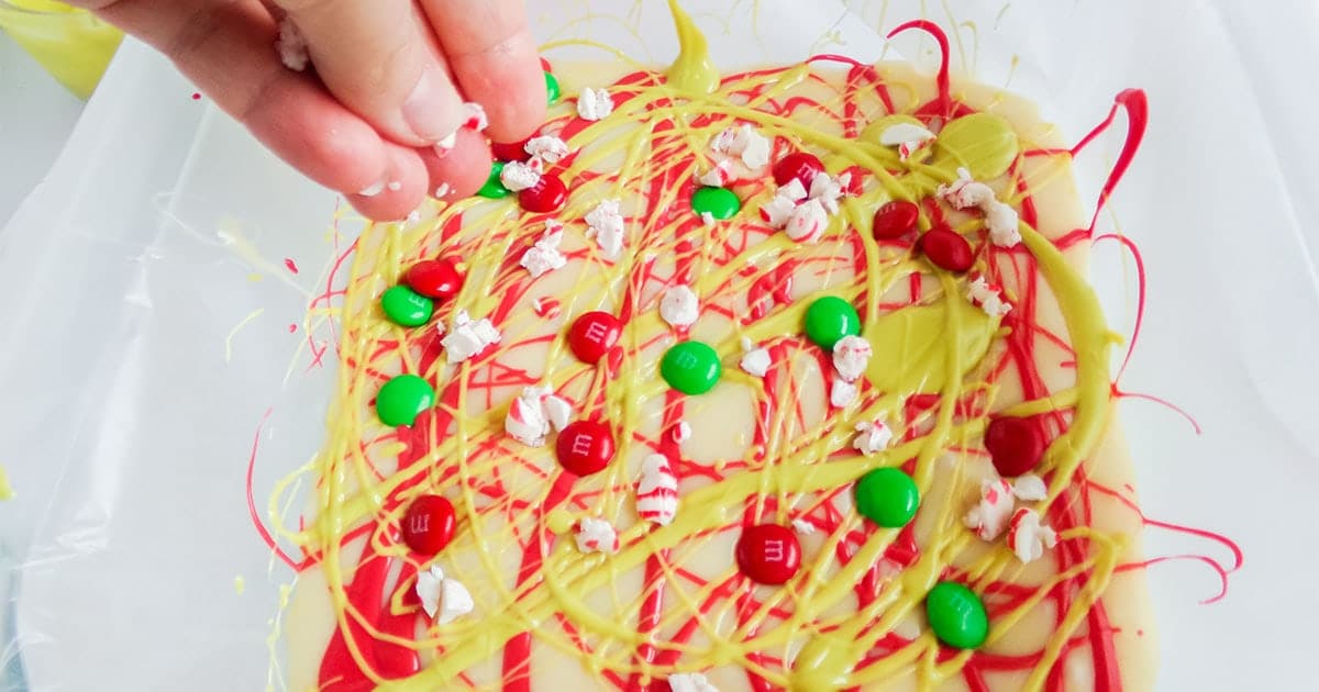 sprinkling candies over grinch fudge for christmas