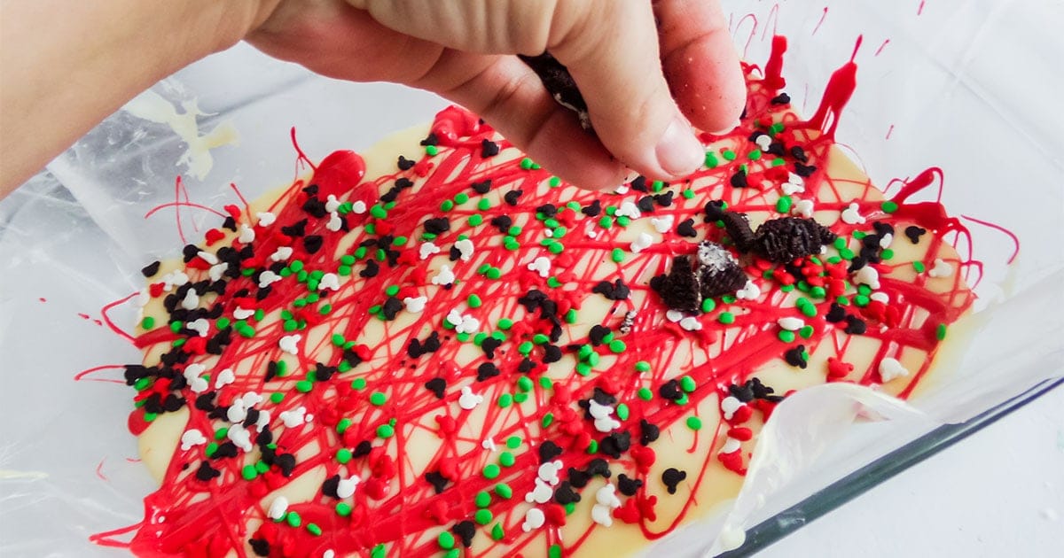 in-process step of adding sprinkles to the top of mickey christmas fudge