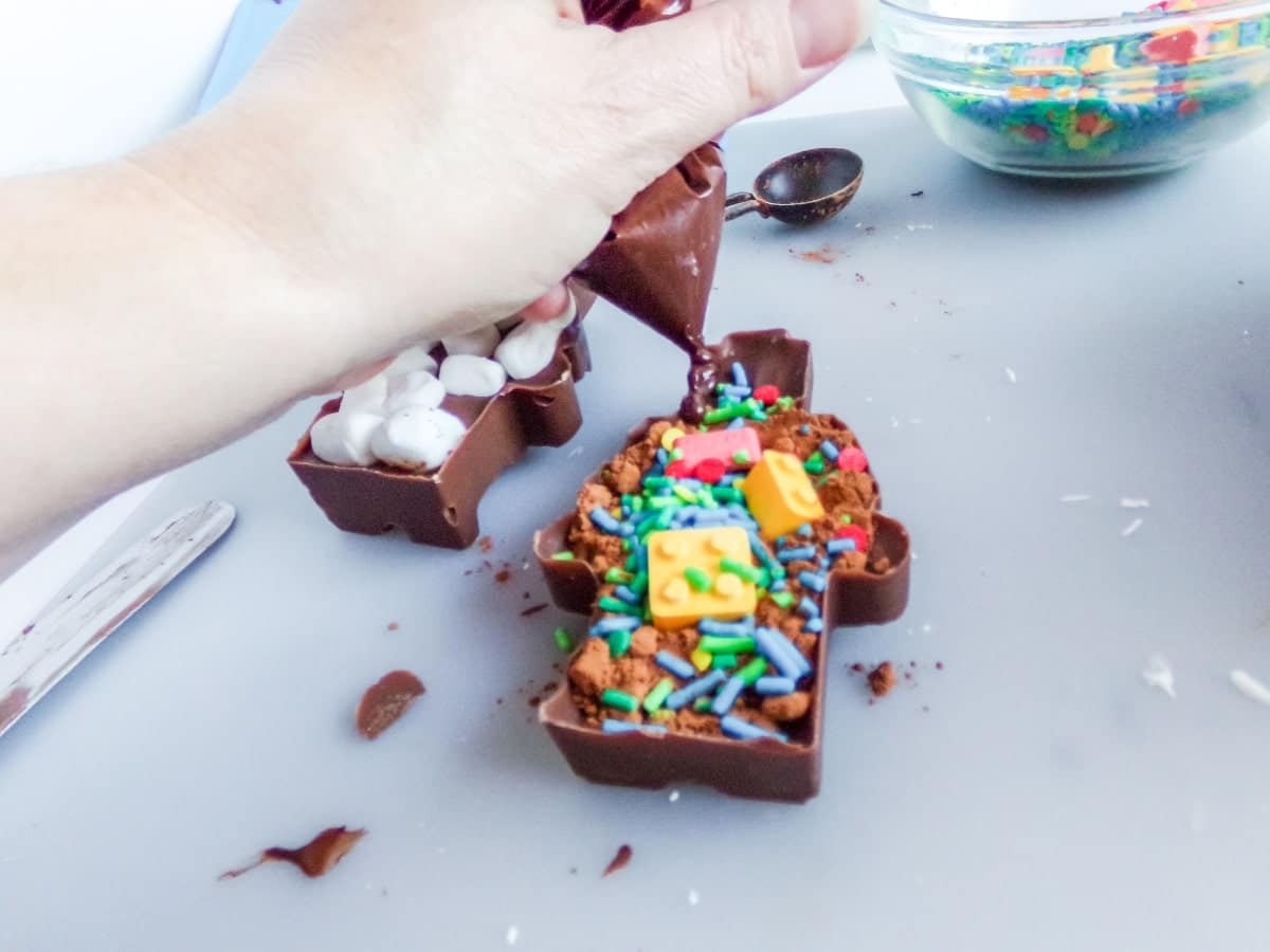 adding chocolate to join the edges of Lego Man Hot Cocoa Bombs