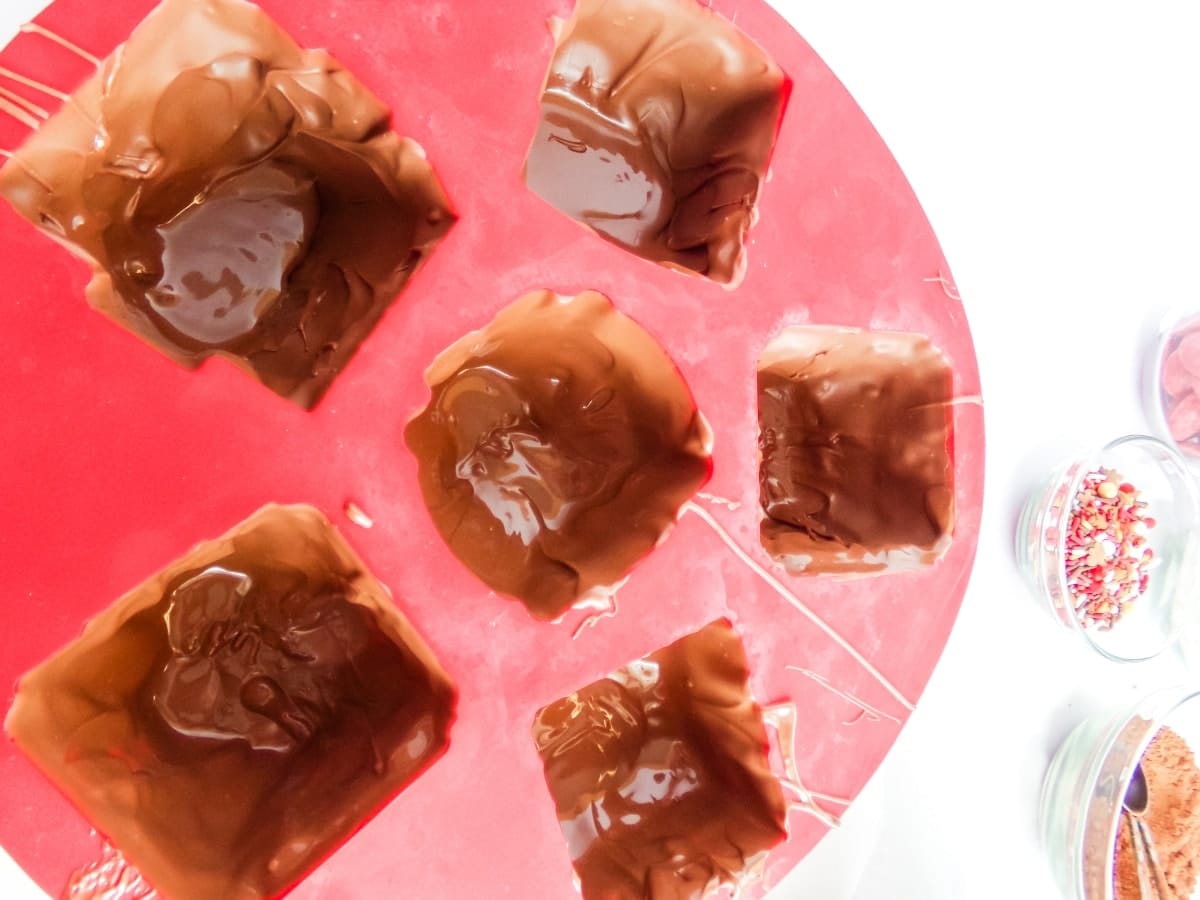 putting chocolate in a mold to make Gingerbread House Hot Cocoa Bombs