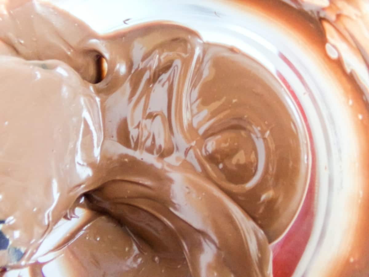 melted chocolate being stirred to make Almond Joy Hot Cocoa Bombs