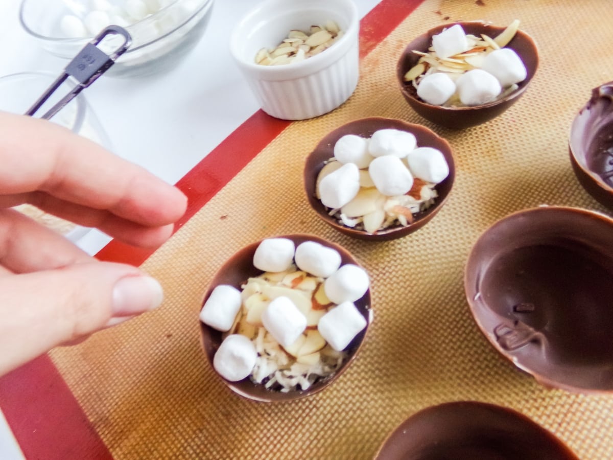 filling hot cocoa bombs to make Almond Joy Hot Cocoa Bombs