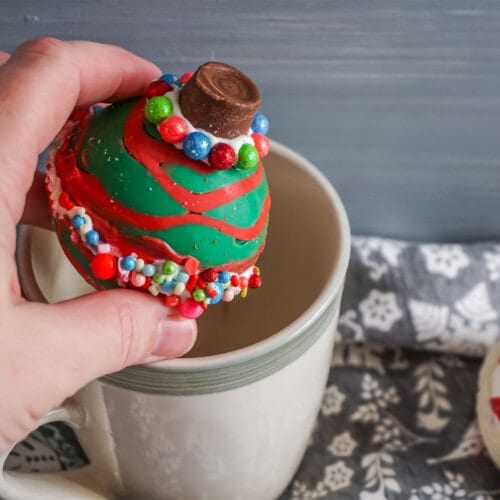 Christmas Ornament Hot cocoa bombs being placed in a mug
