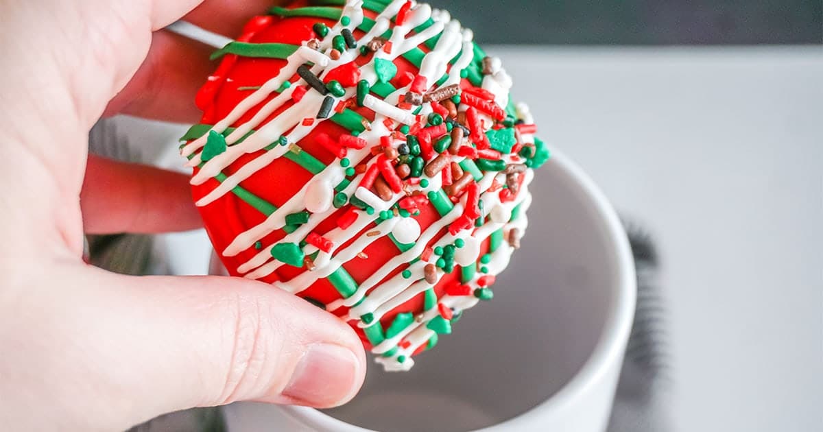 hand putting a Christmas Taffy Hot Cocoa Bombs into a mug