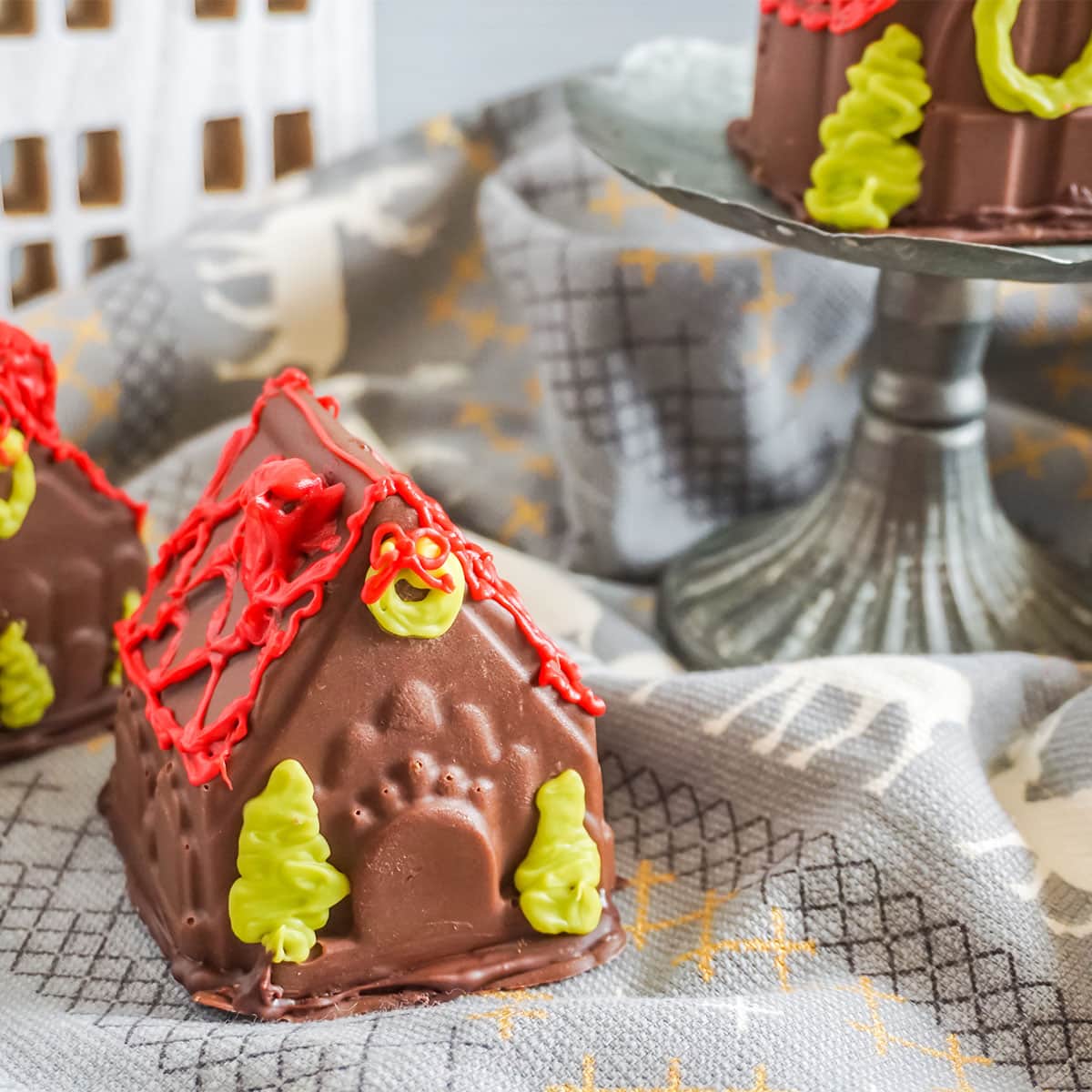 Gingerbread House Hot Cocoa Bombs on a table with a mini house cutout