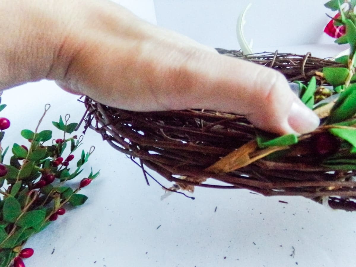 in-process step of attaching greenery to make aMickey Reindeer Wreath