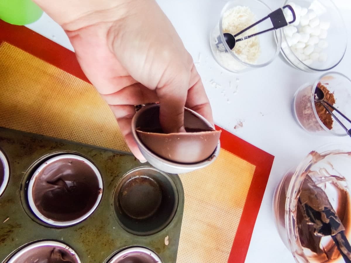 sliding chocolate out of molds to make Mounds Hot cocoa bombs