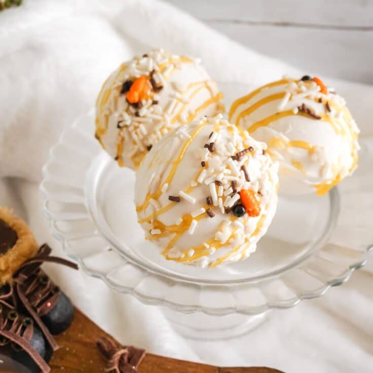 three Snowman Hot Cocoa Bombs on a cupcake stand