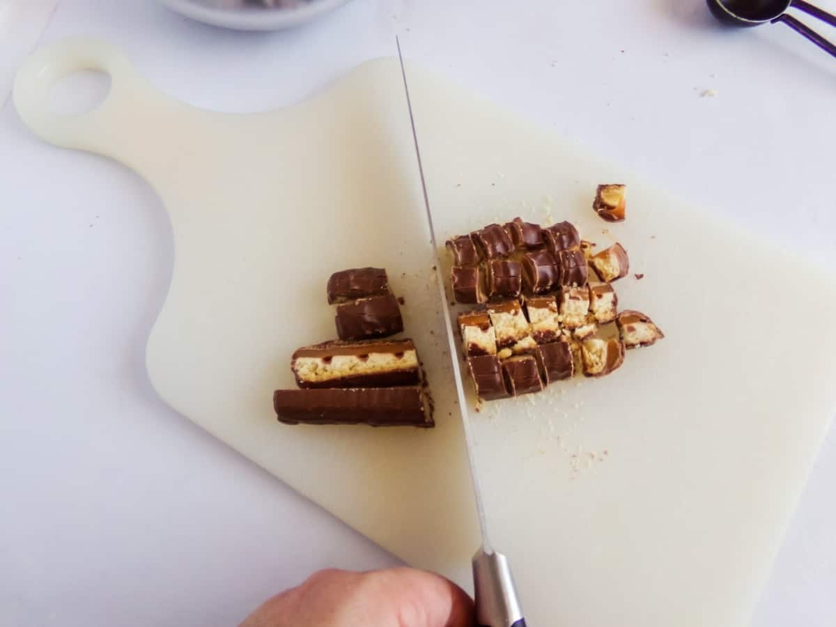 chopping candy bars to make twix hot cocoa bombs