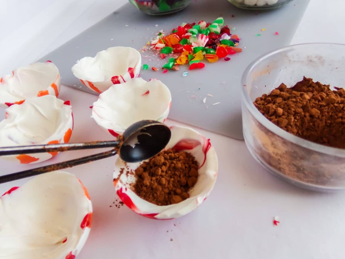 in-process step of filling chocolate cups to make old fashioned Christmas Candy Hot cocoa bombs