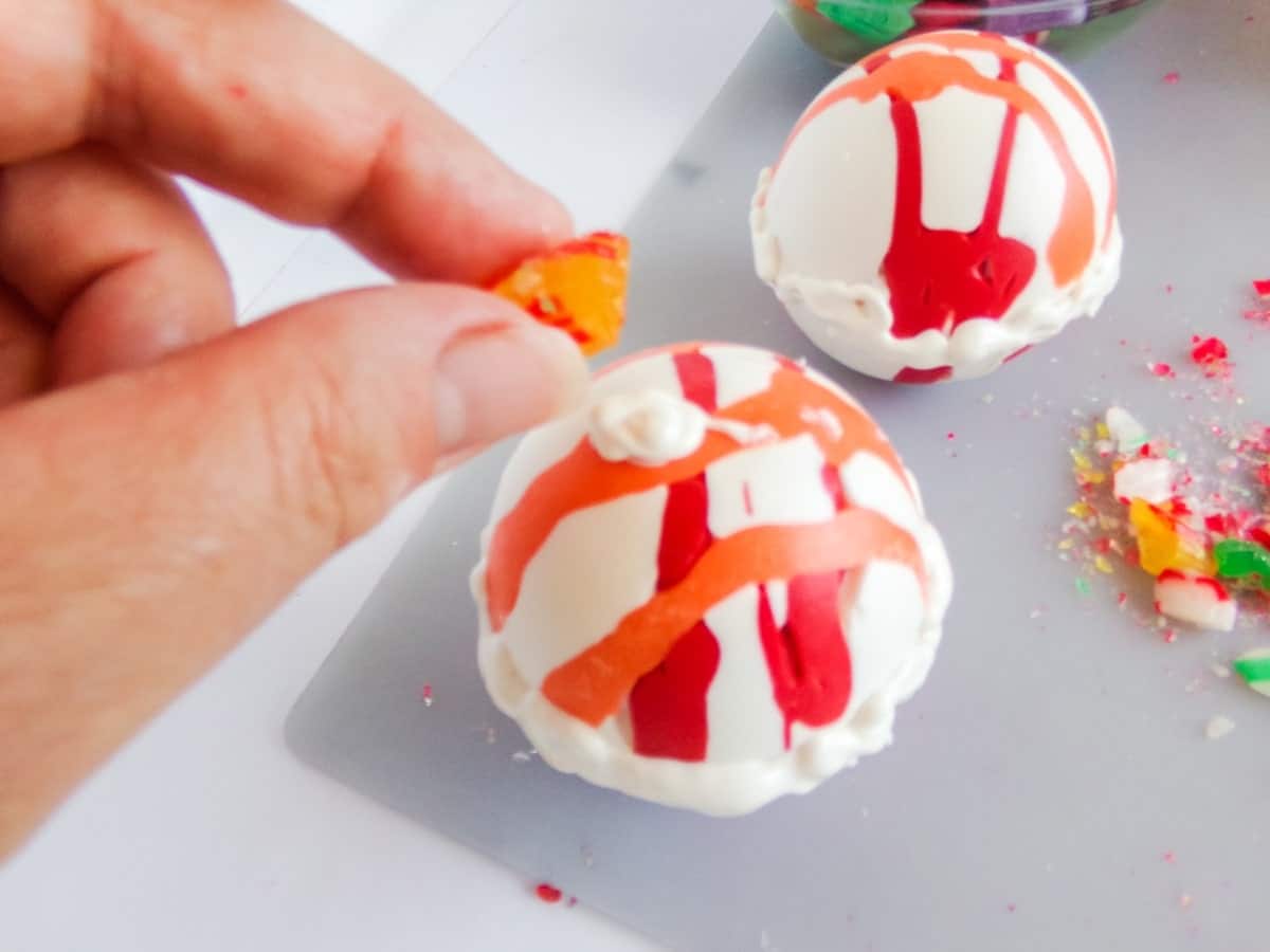 in-process step of adding candy to the top of old fashioned Christmas Candy Hot cocoa bombs