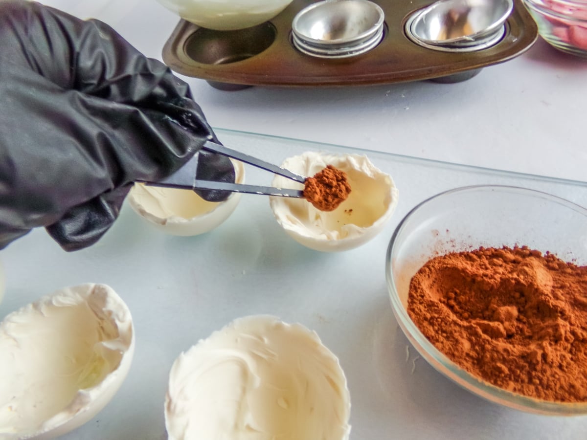 in-process step of filling hot cocoa bombs with hot cocoa mix to make peppermint hot cocoa bombs