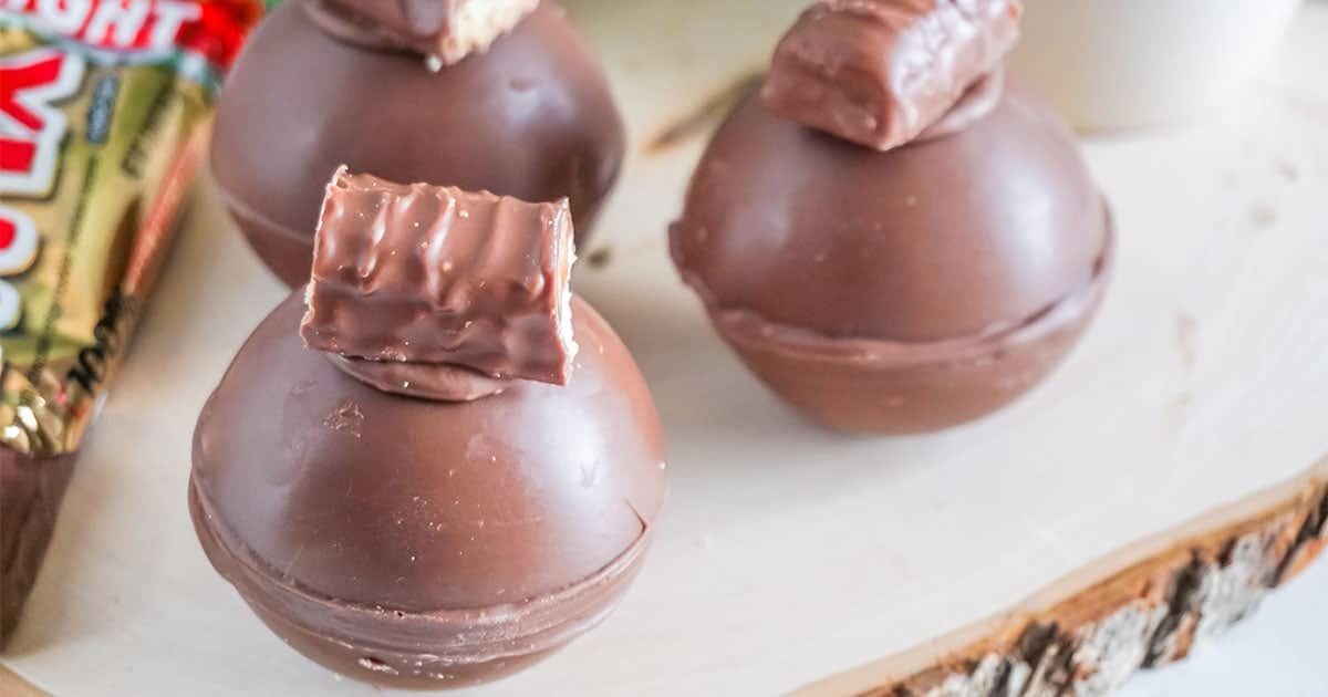 closeup of twix hot cocoa bombs on a wood board