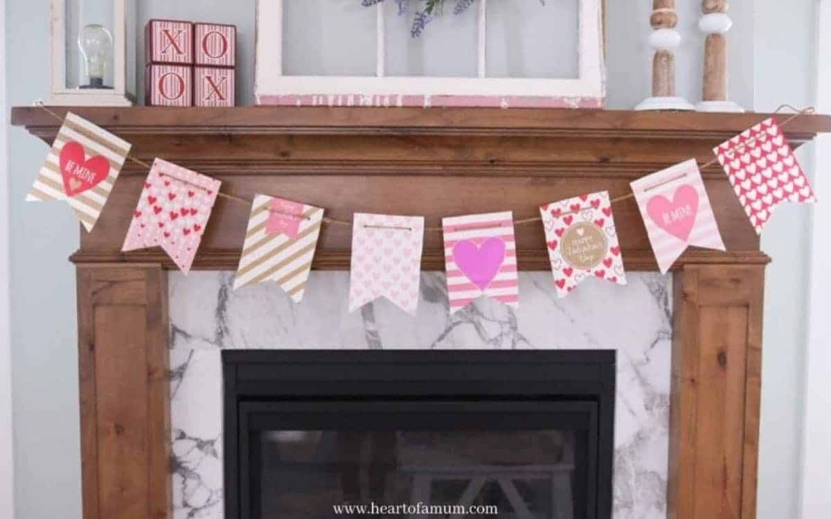 A wooden mantelpiece is pictured. Hanging from it is a garland made of paper flag shapes in different designs