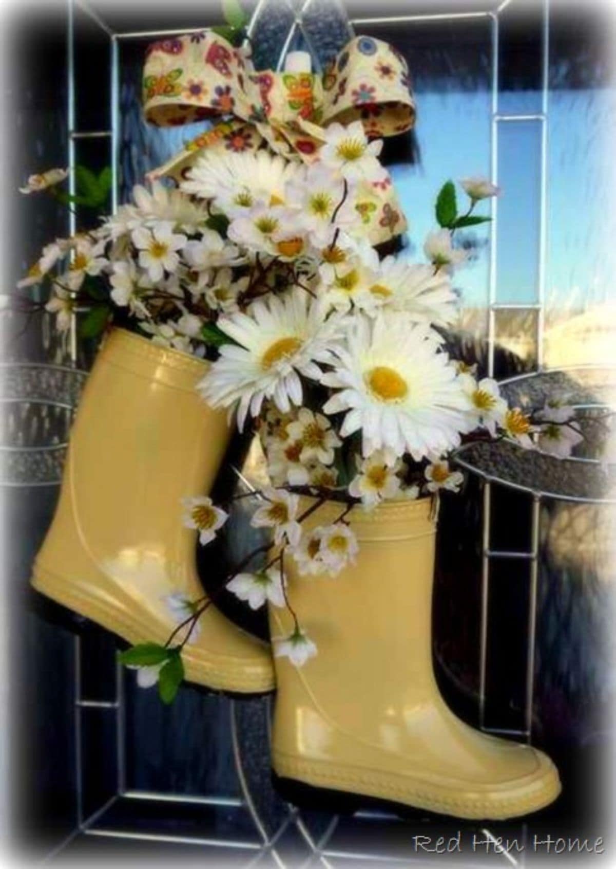 Hanging from a front door are two yellow wellies filled with white and yellow flowers