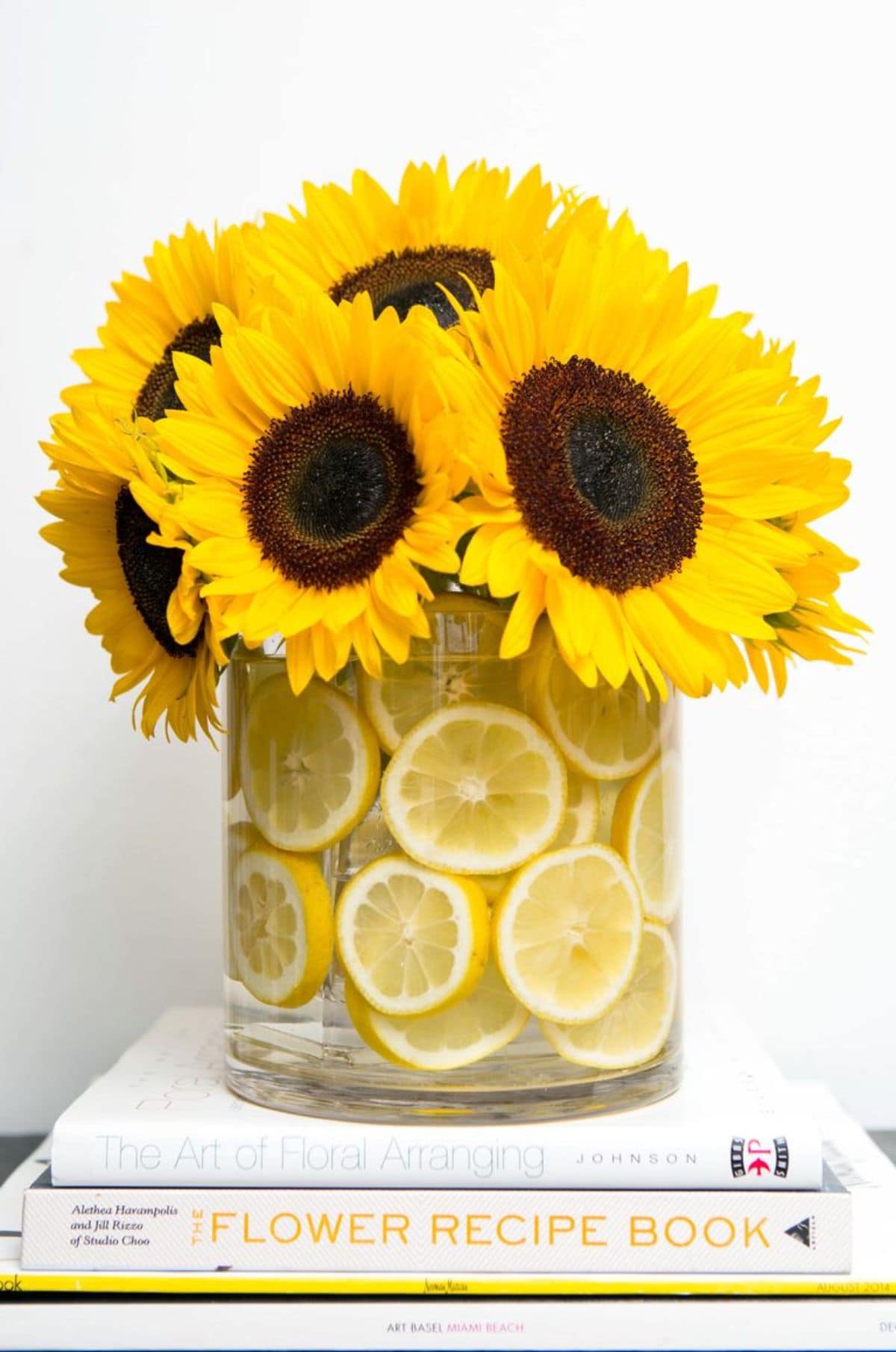 stading ona table is a wide vase filled with lemon slices and sunflowers