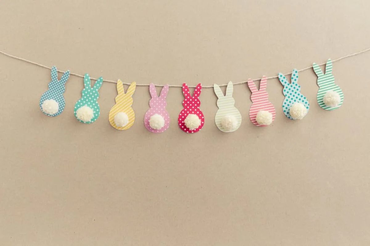 A row of bunnies made of card hanging from a string in blue, yellow, pink, red, white, pink and blue.