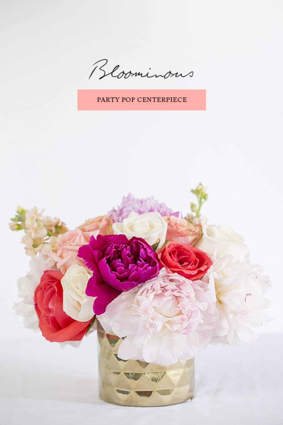 On a white background is a rose gold metal pot filled with white, red and purple flowers