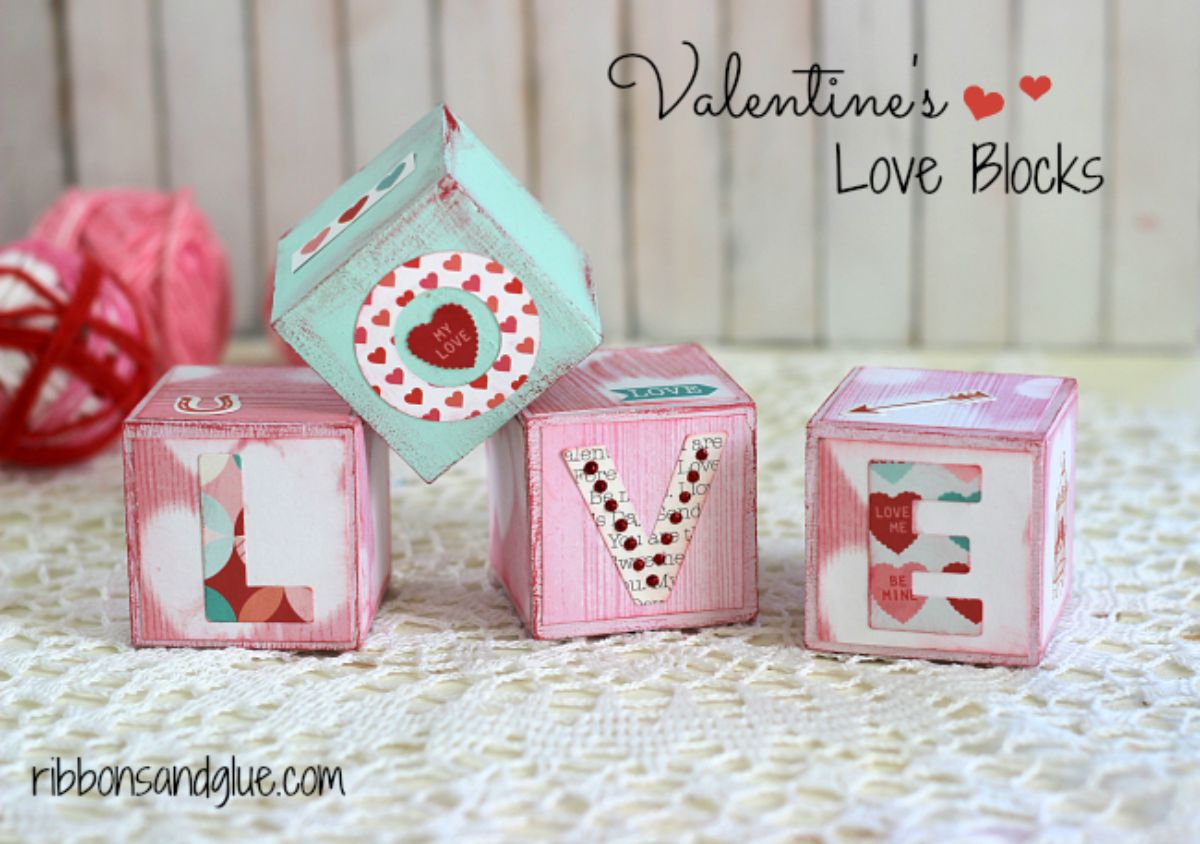 On a cream tablecloth wooden blocks are decorated with patters and the letters L, O, V and E