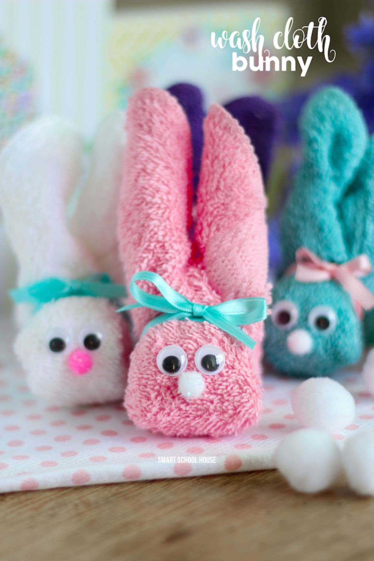 Three bunnies made of differnet colored washcloths sit next to each other