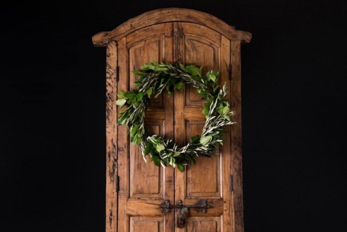 On a wooden carved door hangs a simple green wreath