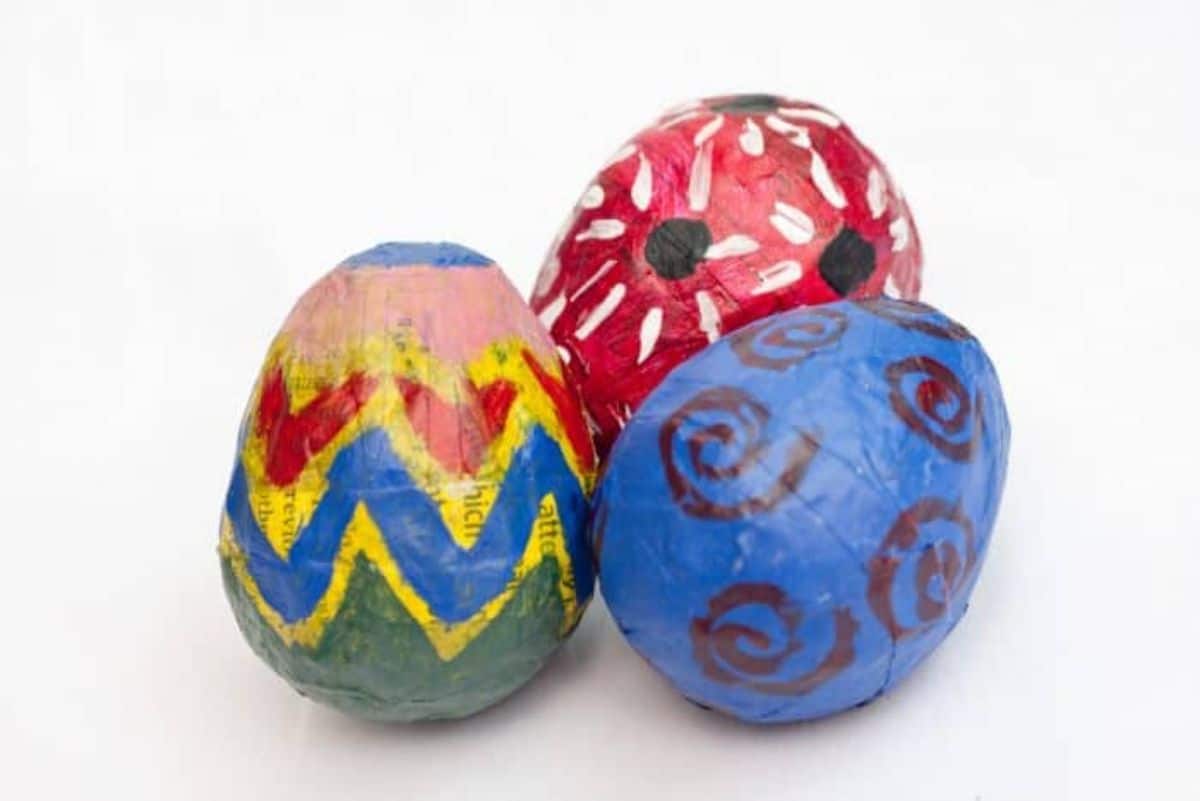 3 eggs sit on a white background. They are decorated in bright colors