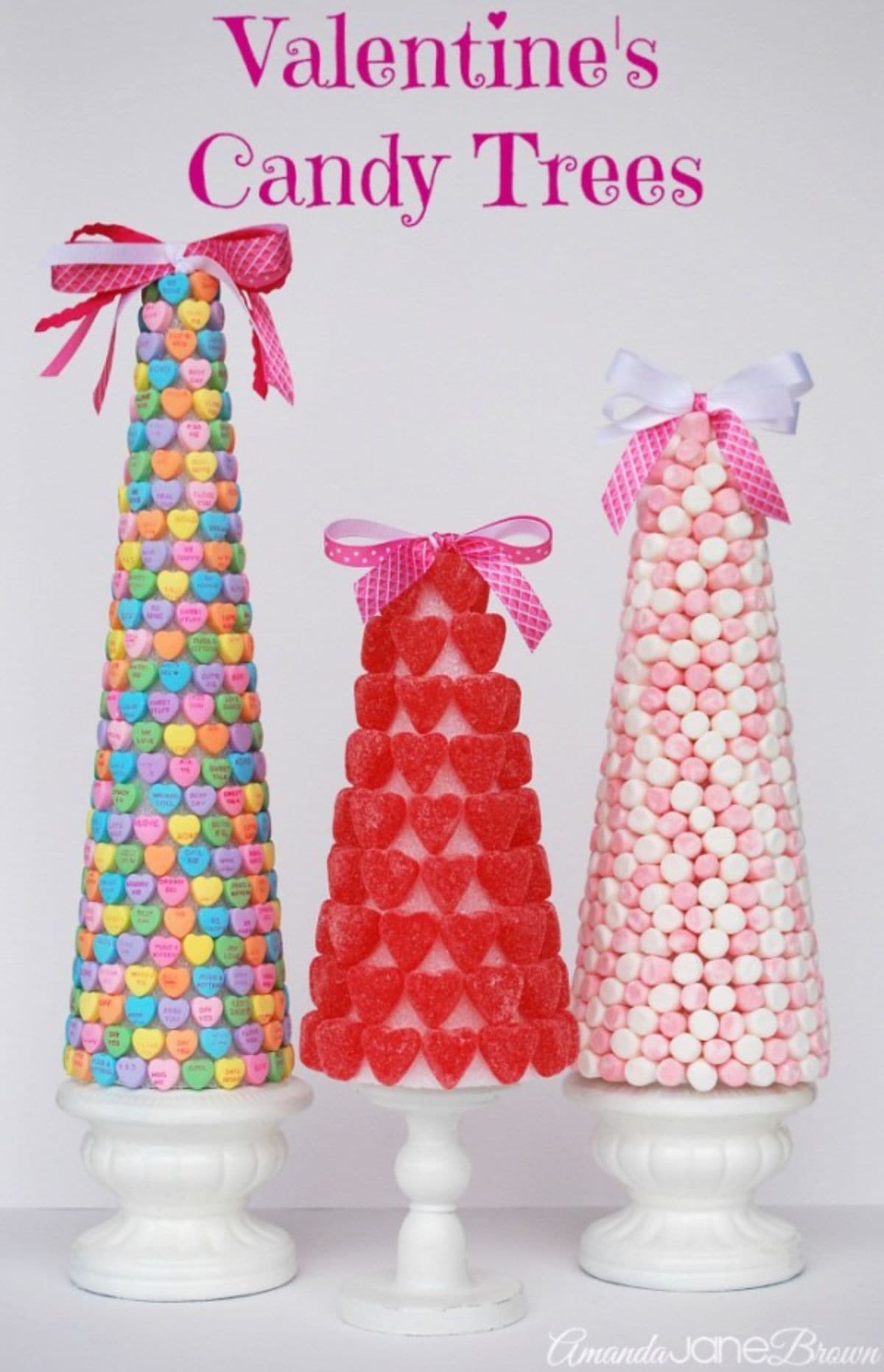 Three cones of varying sizes sit next to each other. On the left is a cone covered in candy hearts, in the middle a cone covered with jelly hearts, on the right a cone covered in sugar balls