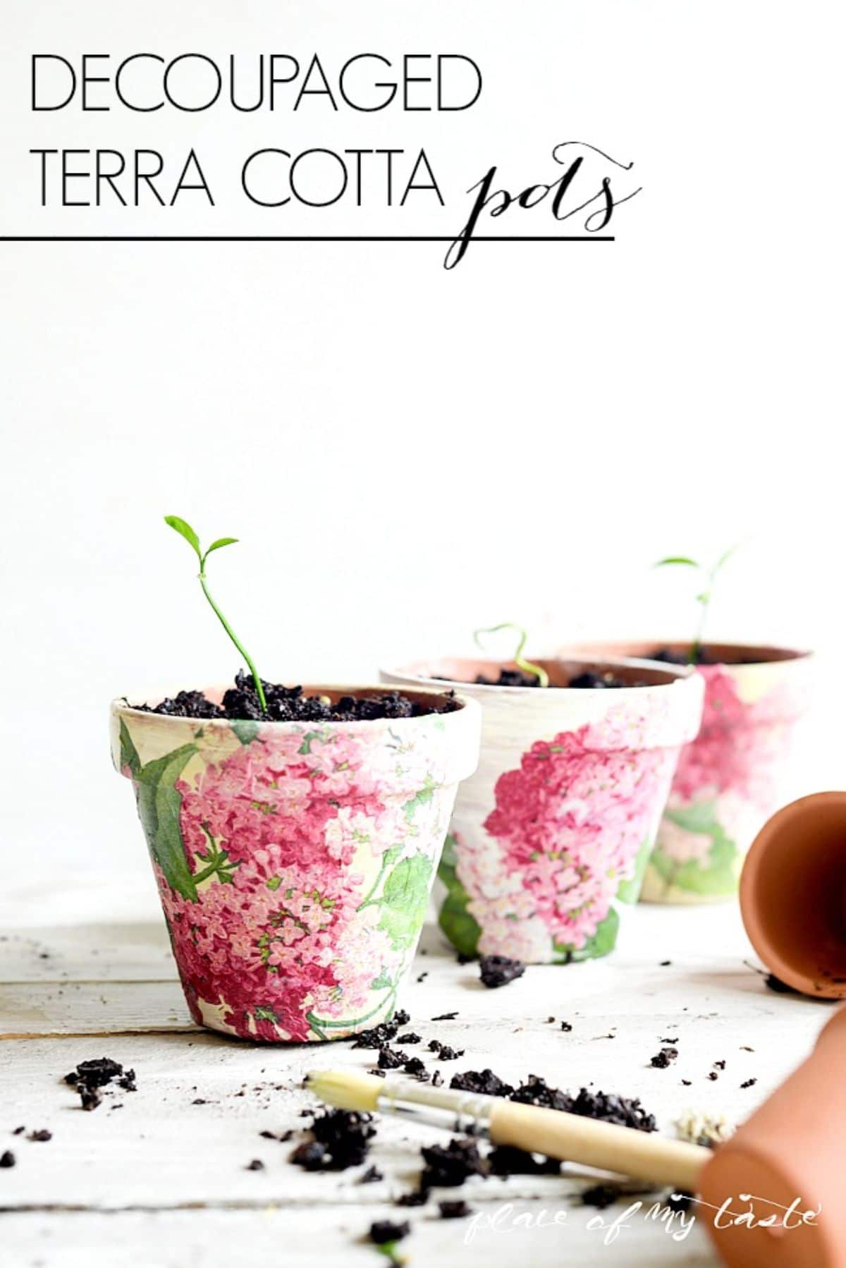 3 plant pots filled with soil have flowers decoupaged around the outside. In the foreground is a trowel with soil on it