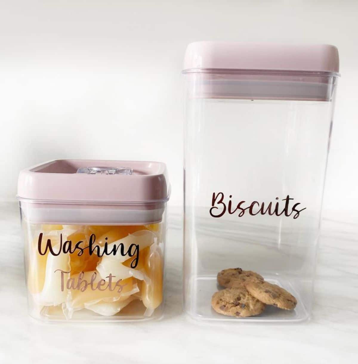 Two glass square pots with white lids. Labelled "washing tablets" and "biscuits"