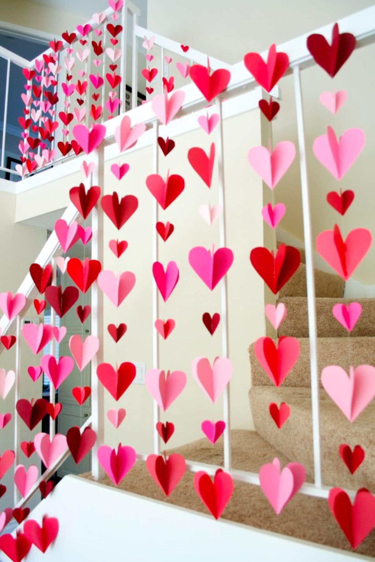 hanging from the top of a shelf are several strings with 3D paper hearts strung vertically from them