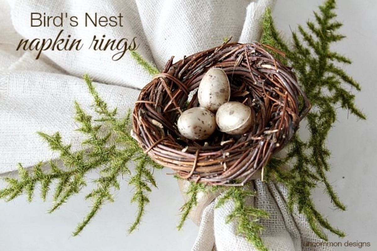 A napkin ring is holding a napkin together, decorated with a birds nest and small eggs