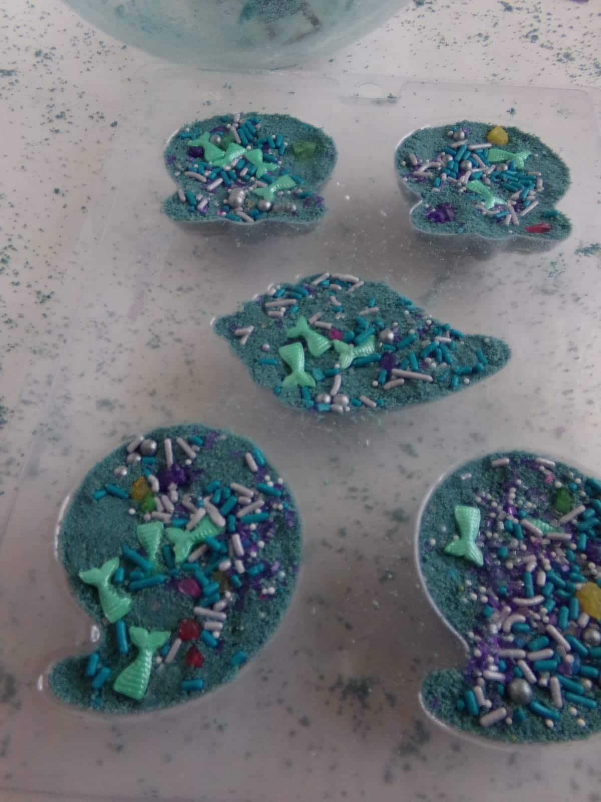 in-process step of filling molds to make mermaid shell bath bombs