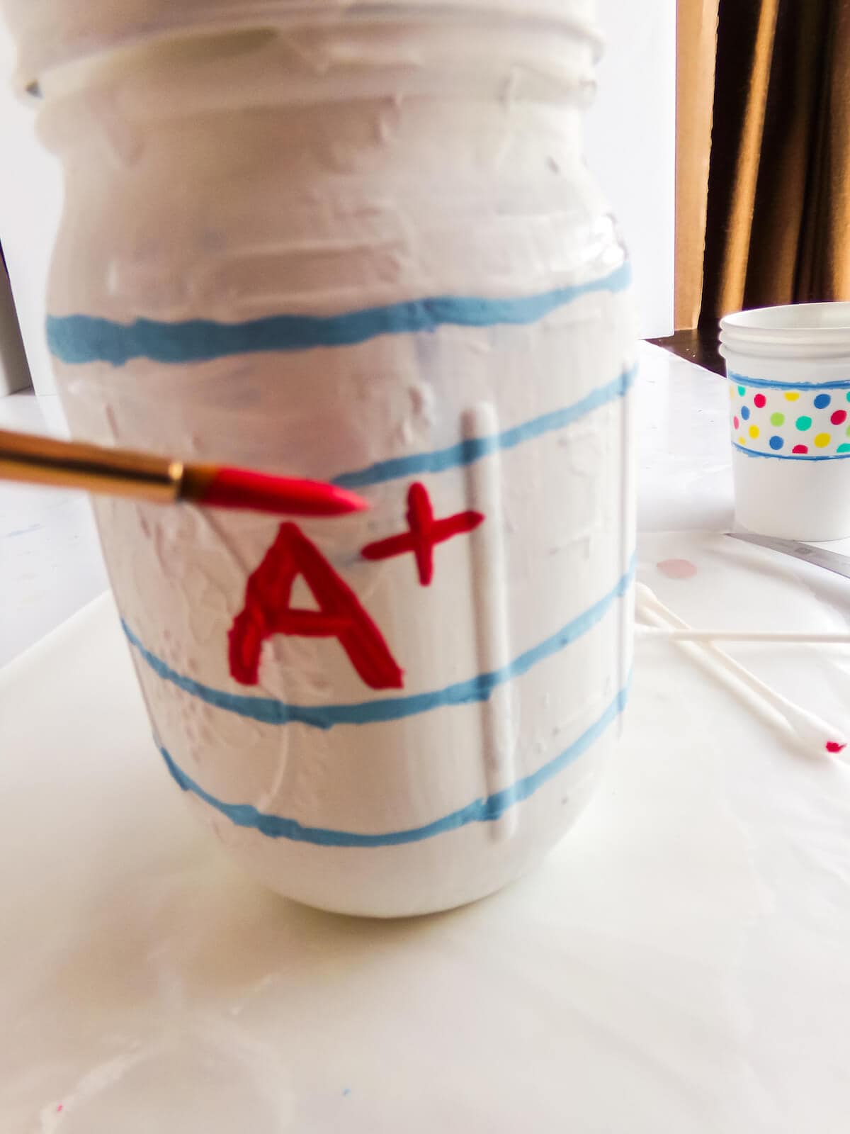 in-process step of painting a paper mason jar