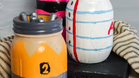 pencil paper and crayon painted jars on a table