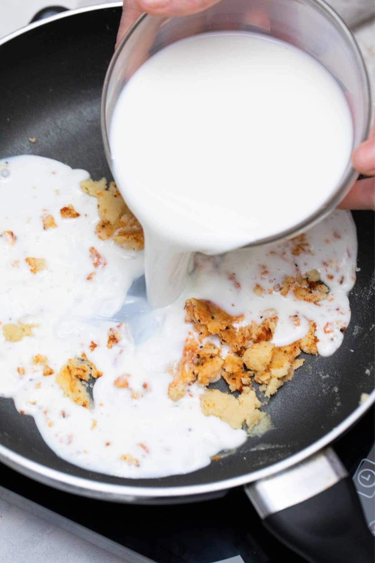 hand pouring milk into skillet