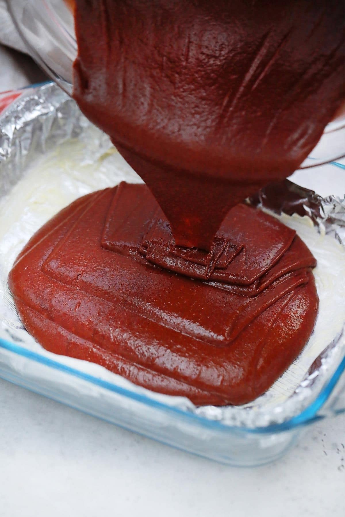 red velvet brownie batter being poured into baking pan