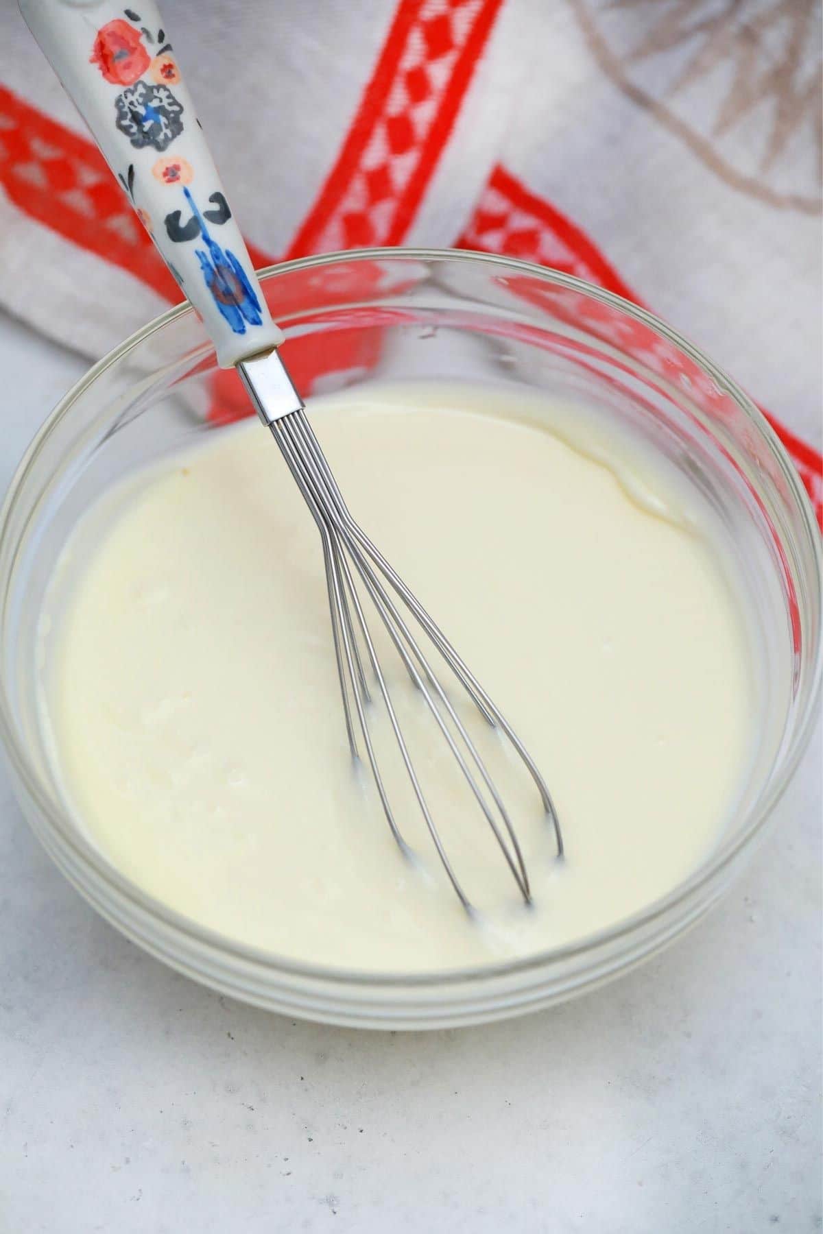 whisk in bowl of cream cheese frosting