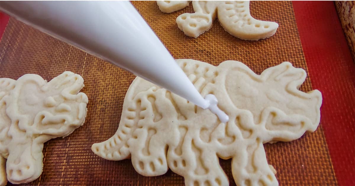 piping icing onto fossil cookies for a dinosaur party
