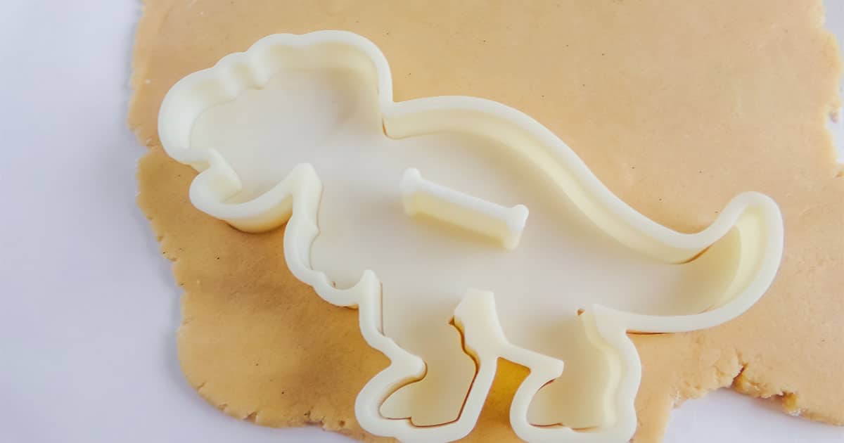 cutting out dinosaur and fossil shapes for fossil cookies