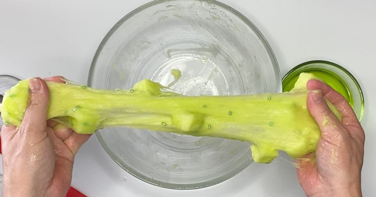 kiwi jelly cube slime being stretched over a bowl