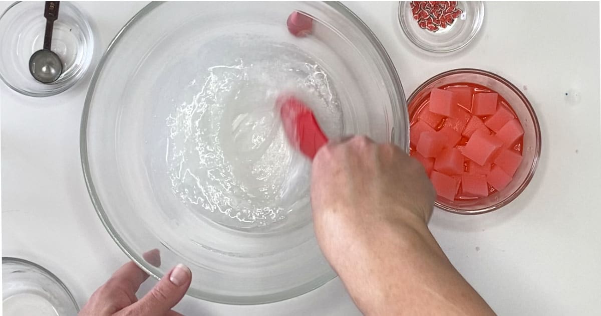mixing ingredients to make watermelon jelly cube slime